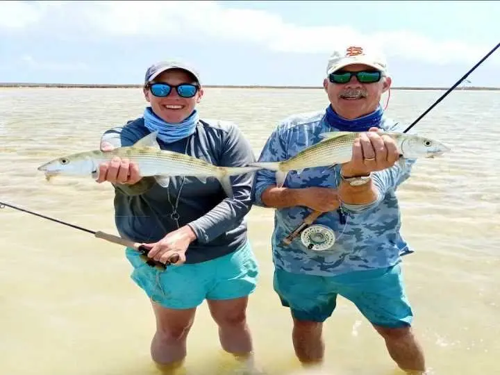 Two anglers displaying fish on the flats