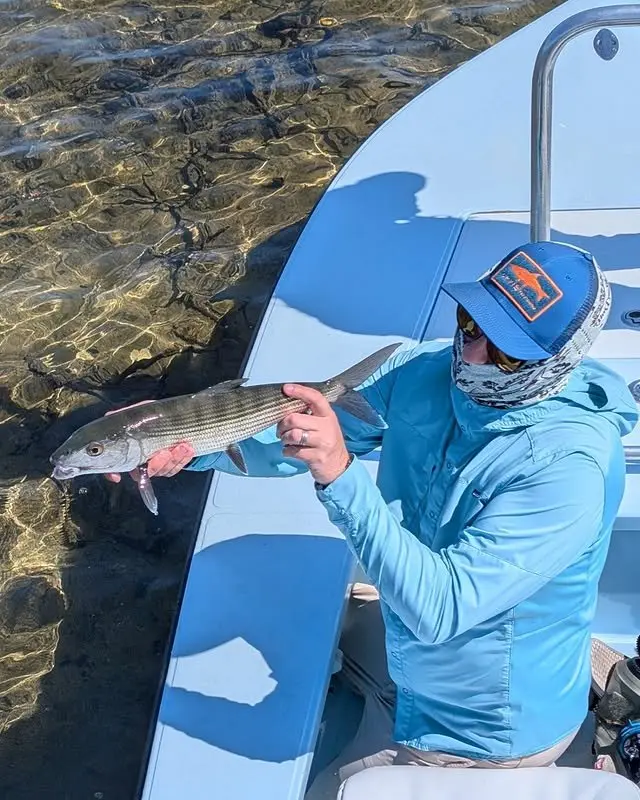 Angler with a fish beside a flats skiff
